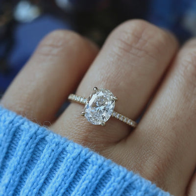 A solid gold engagement ring with an oval moissanite stone.