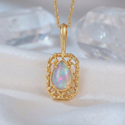 Close-up of a solid gold necklace with a pear-shaped iridescent opal pendant.