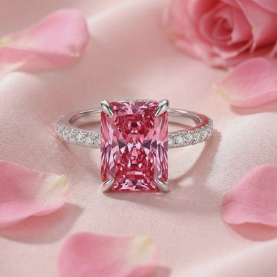 Radiant cut simulated pink tourmaline solid gold ring displayed on pink satin among rose petals.