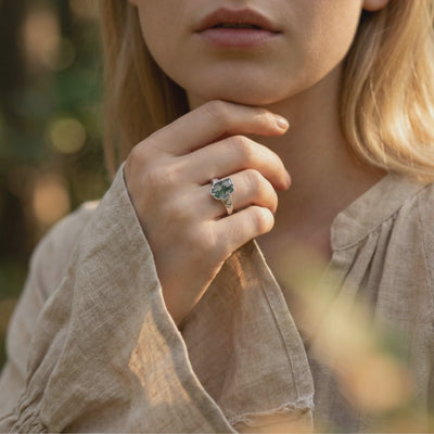 A solid white gold moss agate ring with a leaf design.