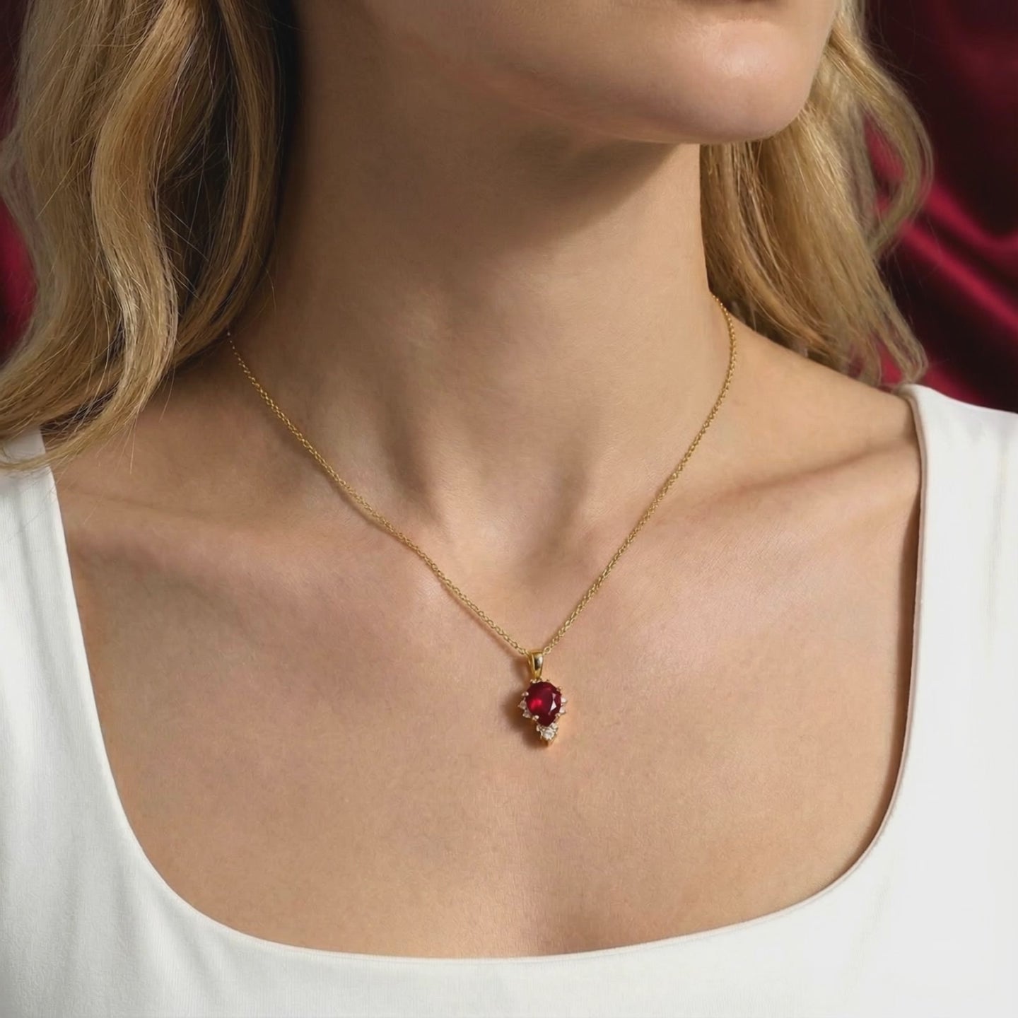 A solid gold necklace with a pear cut simulated ruby.