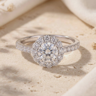 Close-up video frame of the silver-colored round floral halo ring resting on a beige textured stone slab.
