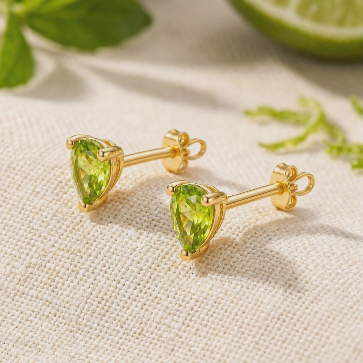 Rotating view of pear-cut green simulated peridot stud earrings in yellow gold with butterfly backs.