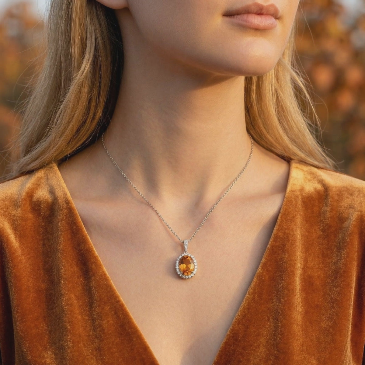 Woman wearing an oval simulated topaz halo necklace in solid white gold.
