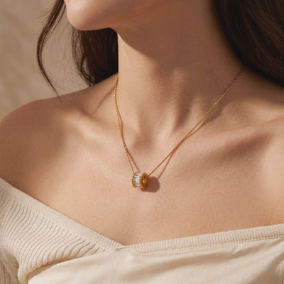 Model wearing the gold-tone Elyndelle necklace with a wheel pendant set with clear baguette-cut stones.