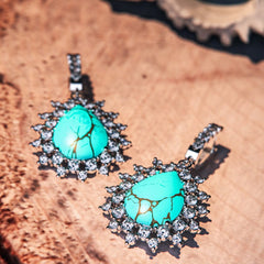 Blue Lagoon Turquoise Earrings featuring turquoise stones set in S925 sterling silver laying on flat surface in close up high detail view
